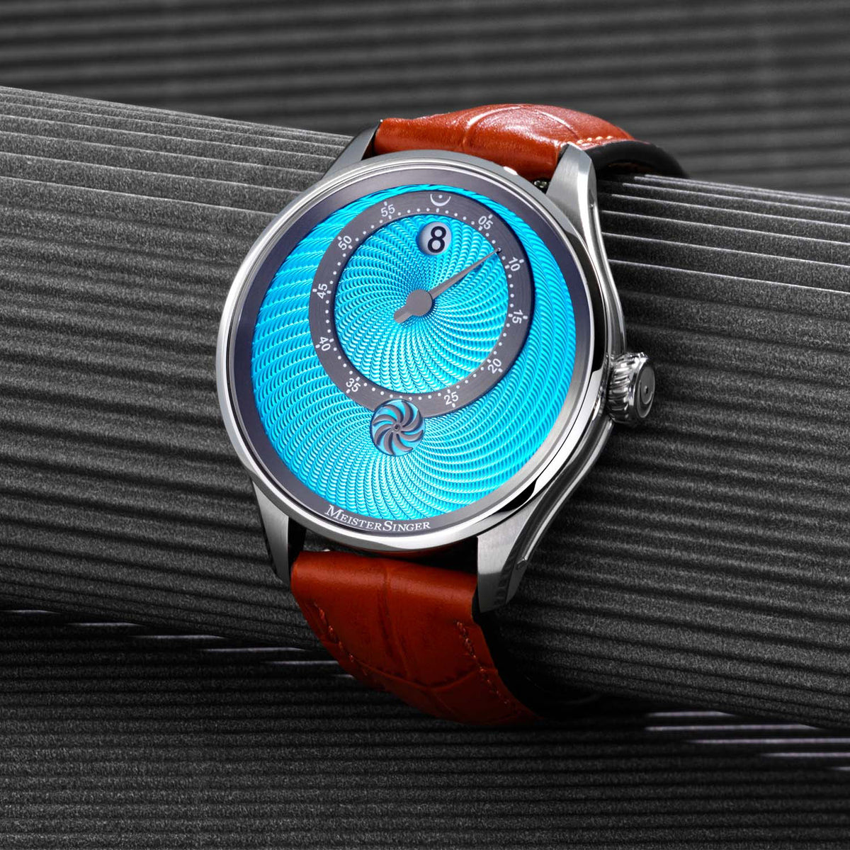 MeisterSinger Panthero Jumping Hour with light blue hand-guilloché dial on a ribbed grey surface